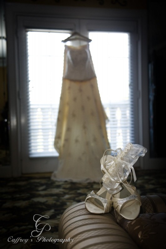 Elegant brides shoes and dress hanging in the bridal room at Cindy's Palace.