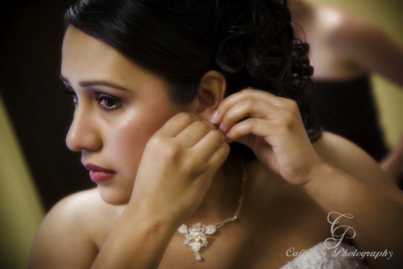 Captivating bride putting on her jewelery before her gorgeous wedding at Cindy's Palace in rosenberg Tx