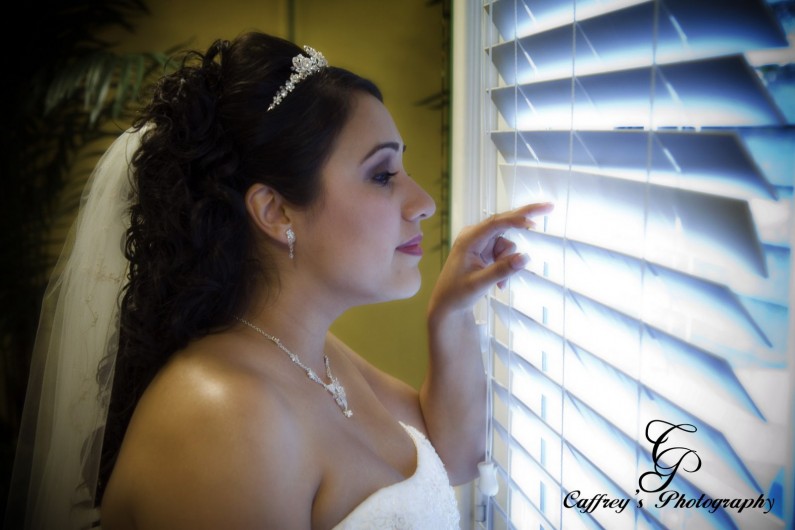 Stunning bride looking out the blinds in the brides room at Cindy's Palace.