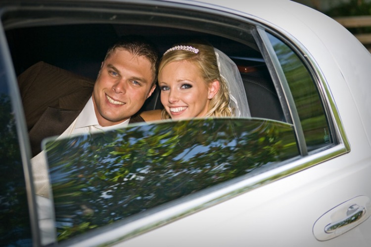 Stunning bride and her groom looking out the window of the white limo.