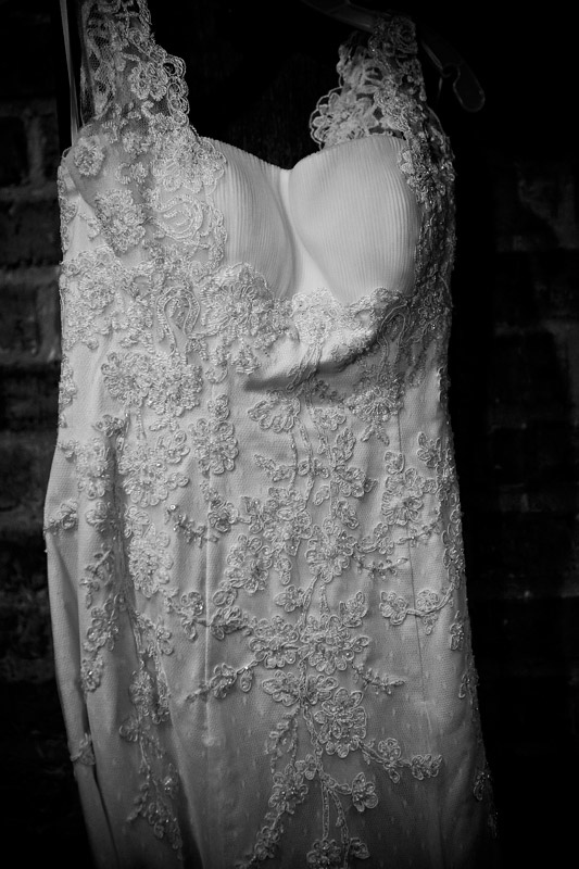 Exquisite lace wedding gown hanging in the brides room. 
