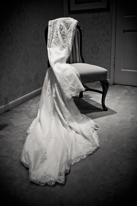 Elegant brides dress draped over a chair at the Courtyard on St James