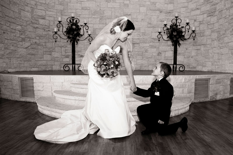 Cute photo with the ring bearer on one knee in front of the bride. 