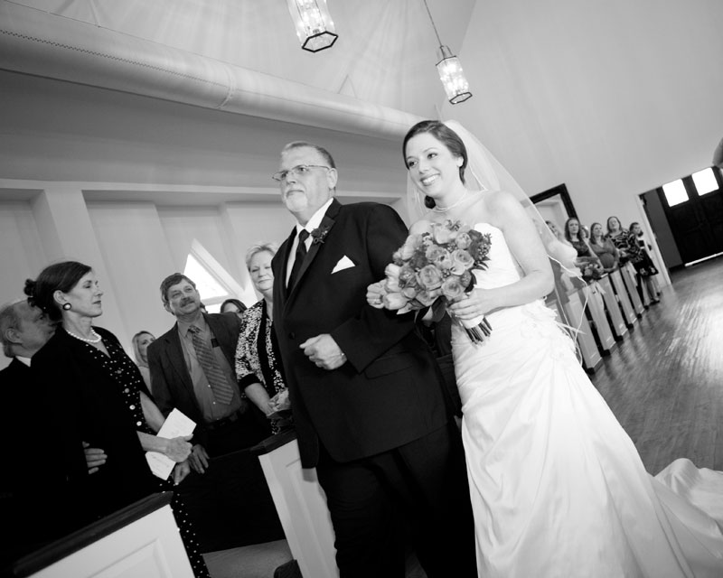Happy bride walking with her father down the aisle in the chapel at Briscoe Manor.