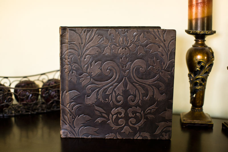 Brown leather wedding album cover with a raised floral design.