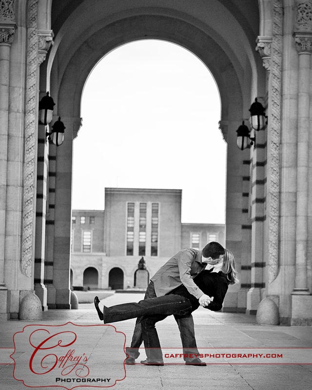 Groom dipping his bride during their engagement session under the arch at Rice University.