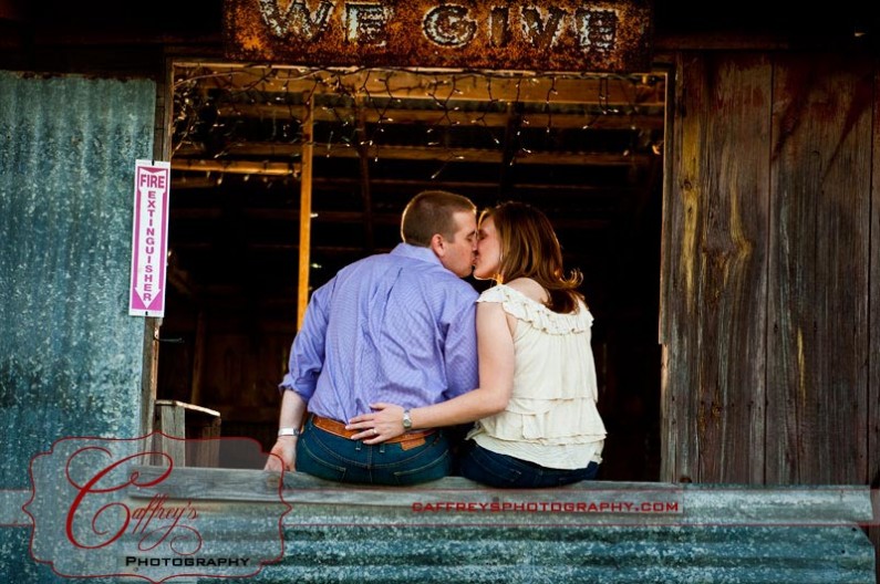 Engaged couple kissing in the barn window. 