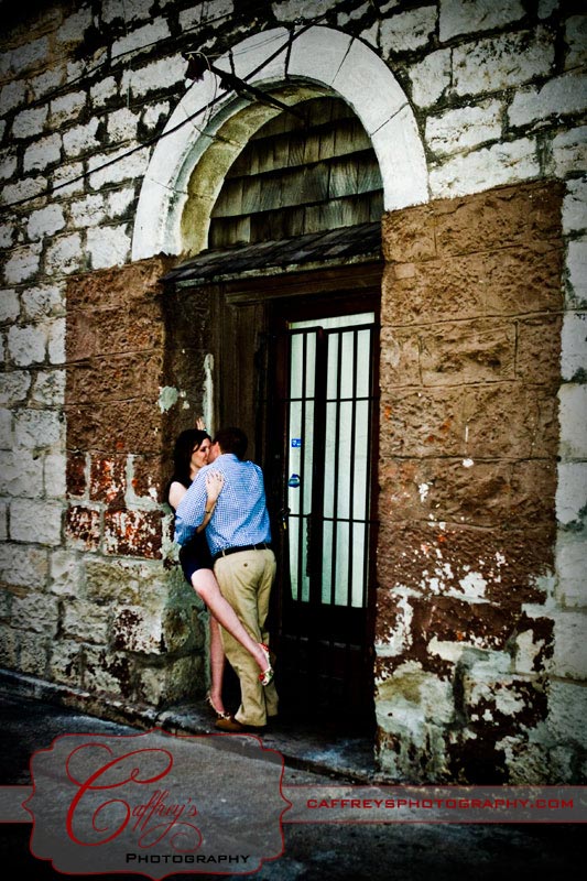 Hot engaged couple kissing under the arched doorway.