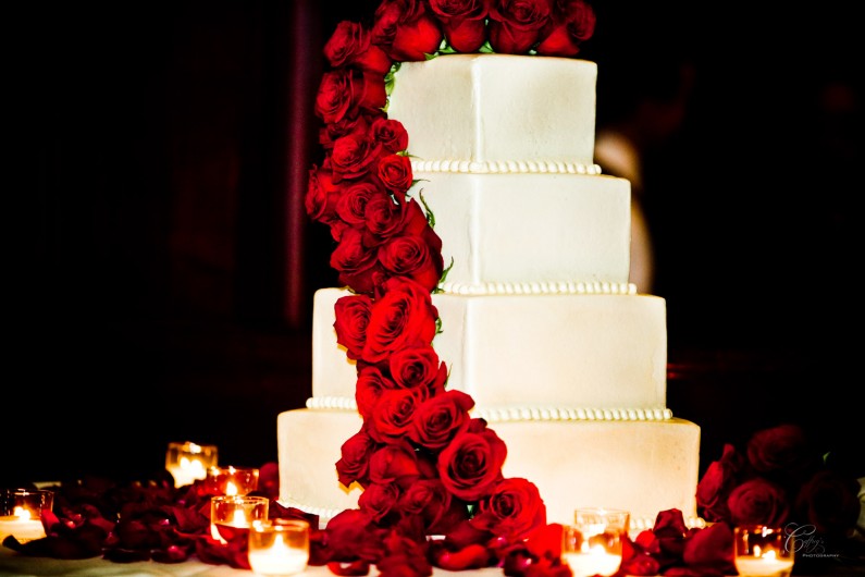 Gorgeous brides cake at her wedding with a cascade of beautiful red roses. 